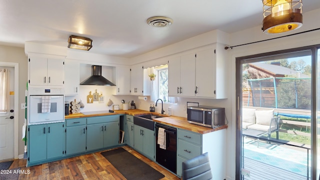 kitchen with dark hardwood / wood-style floors, wall chimney exhaust hood, butcher block countertops, black dishwasher, and white oven