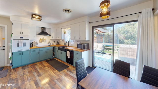 kitchen featuring dark hardwood / wood-style floors, oven, wooden counters, wall chimney exhaust hood, and dishwasher