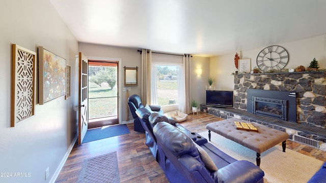 living room with dark hardwood / wood-style flooring and a stone fireplace