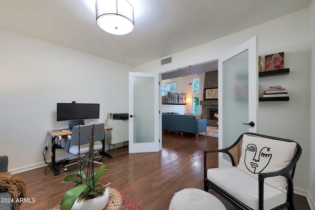 office with dark hardwood / wood-style floors and a large fireplace