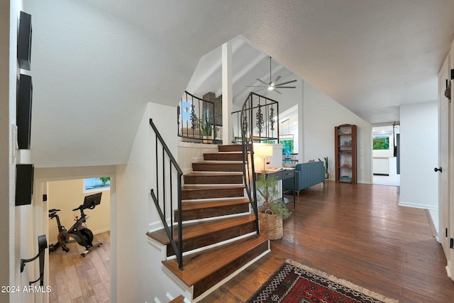 stairs with ceiling fan, lofted ceiling with beams, a textured ceiling, and wood-type flooring