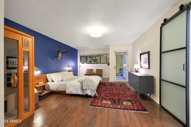 bedroom featuring a barn door and dark hardwood / wood-style floors