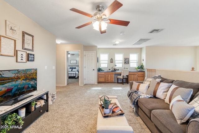 living room with ceiling fan, light colored carpet, and built in desk