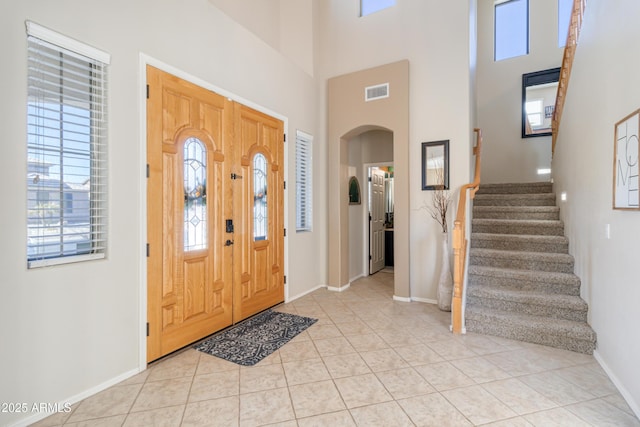 entryway featuring a towering ceiling and light tile patterned floors