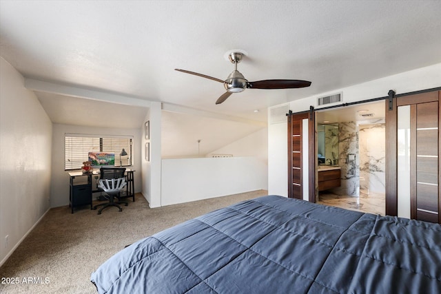 bedroom featuring ceiling fan, connected bathroom, a barn door, and carpet flooring