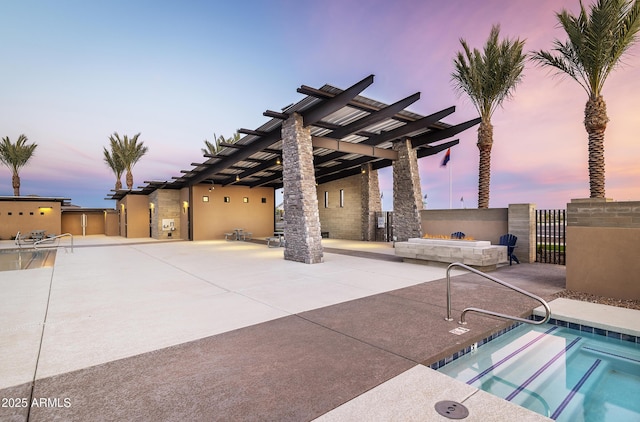 patio terrace at dusk featuring a community hot tub and a pergola