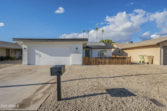 ranch-style house with a garage and solar panels