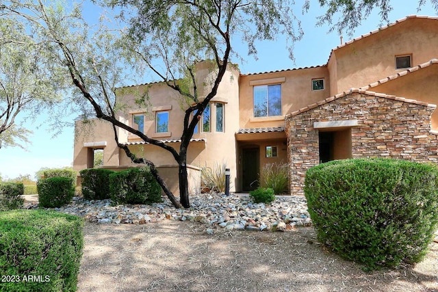 mediterranean / spanish house with stone siding and stucco siding