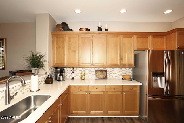 kitchen with light countertops, stainless steel fridge, backsplash, and a sink