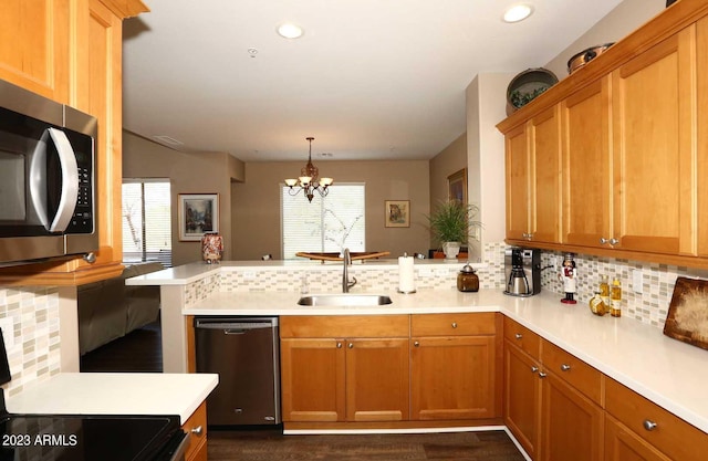 kitchen with a sink, backsplash, stainless steel appliances, a peninsula, and light countertops