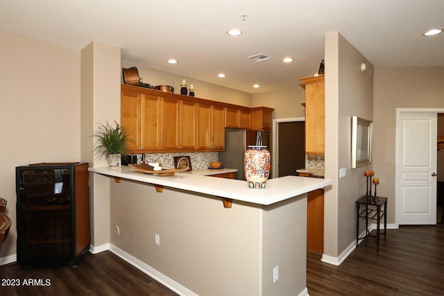 kitchen featuring visible vents, beverage cooler, light countertops, a peninsula, and freestanding refrigerator