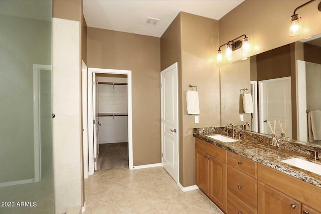 bathroom featuring double vanity, tile patterned floors, a walk in closet, and a sink