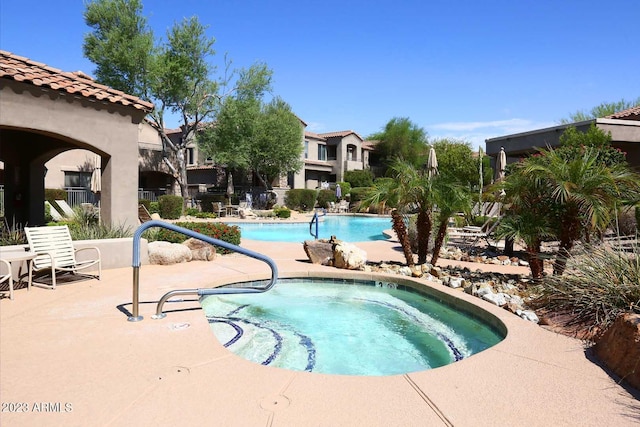 pool with a patio and a hot tub