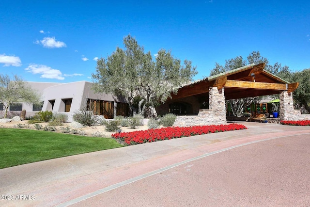 exterior space featuring stucco siding, stone siding, and a front yard