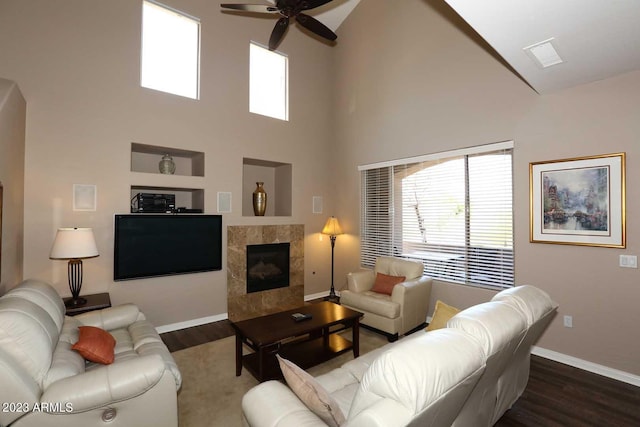 living room with ceiling fan, a tile fireplace, baseboards, and wood finished floors