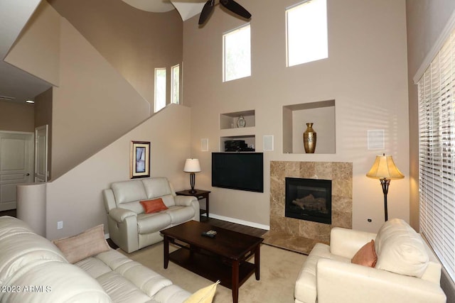 living room with a high end fireplace, a high ceiling, and ceiling fan