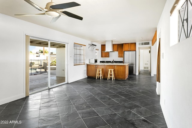 kitchen featuring kitchen peninsula, range hood, stainless steel fridge, ceiling fan, and sink