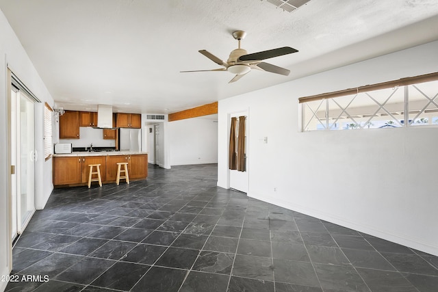 unfurnished living room with a healthy amount of sunlight, ceiling fan, and a textured ceiling