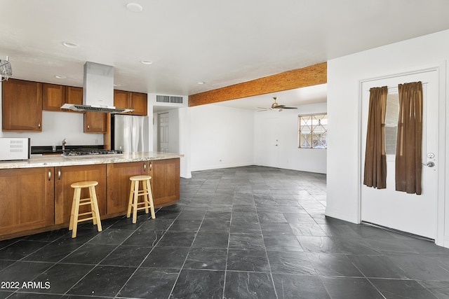 kitchen featuring island exhaust hood, a breakfast bar area, appliances with stainless steel finishes, kitchen peninsula, and ceiling fan