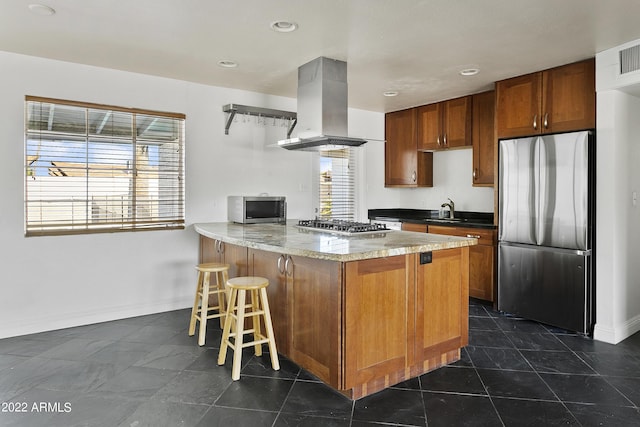 kitchen featuring island exhaust hood, stainless steel appliances, kitchen peninsula, a breakfast bar, and sink