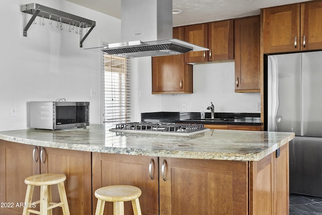 kitchen with sink, island exhaust hood, kitchen peninsula, a breakfast bar area, and appliances with stainless steel finishes