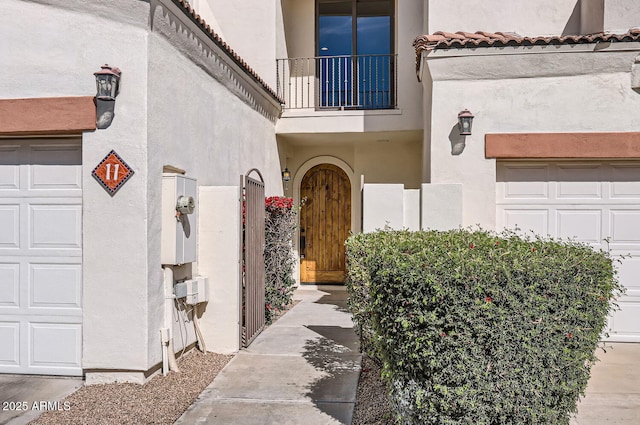 entrance to property with a garage and stucco siding