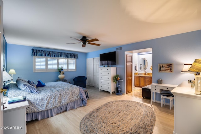 bedroom featuring ceiling fan, a closet, connected bathroom, and light hardwood / wood-style flooring