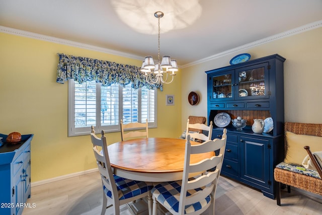 dining room with a notable chandelier, crown molding, and light hardwood / wood-style flooring