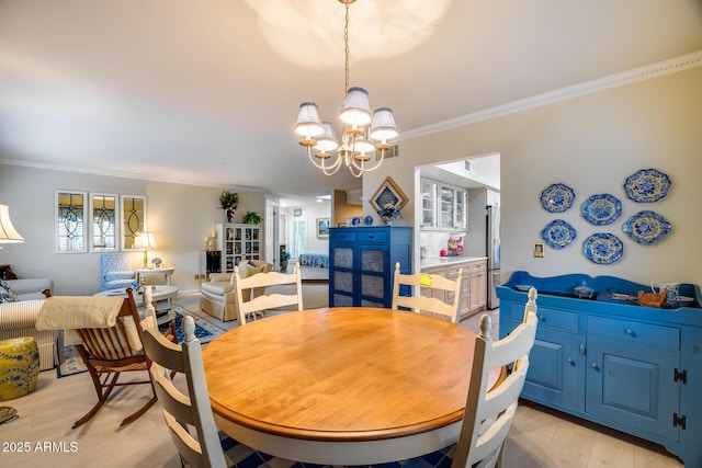 dining space with crown molding, an inviting chandelier, and light wood-type flooring