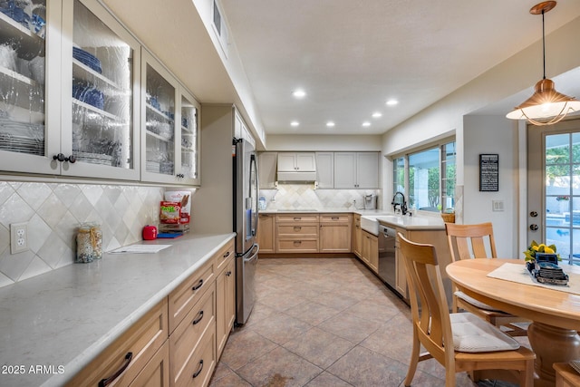 kitchen with light brown cabinetry, sink, hanging light fixtures, appliances with stainless steel finishes, and backsplash