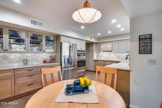 kitchen with pendant lighting, sink, dark tile patterned flooring, decorative backsplash, and stainless steel appliances