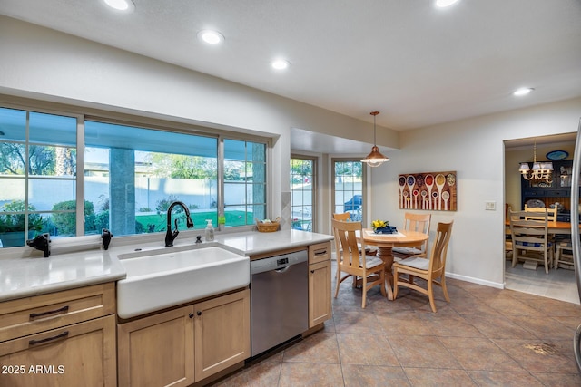 kitchen featuring pendant lighting, sink, light tile patterned floors, stainless steel dishwasher, and light brown cabinets