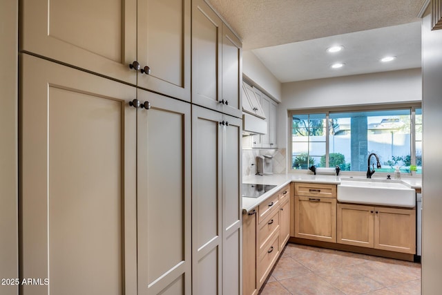 kitchen with light brown cabinetry, tasteful backsplash, sink, light tile patterned floors, and black electric cooktop