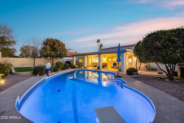 pool at dusk with a diving board and a patio