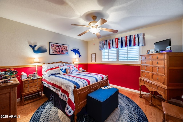 bedroom with hardwood / wood-style flooring, ceiling fan, and a textured ceiling