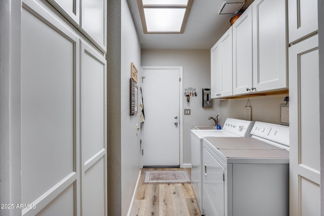 laundry room featuring cabinets, light wood-type flooring, and washer and clothes dryer