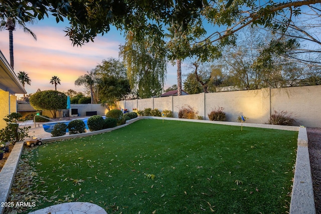 yard at dusk featuring a fenced in pool