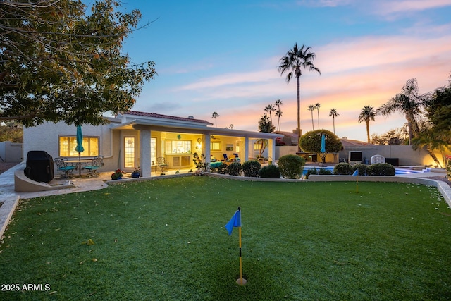 back house at dusk with a patio area