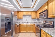 kitchen with sink, light stone countertops, stainless steel appliances, and light tile patterned floors