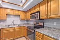 kitchen with tasteful backsplash, sink, a tray ceiling, and stainless steel appliances