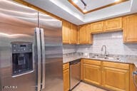 kitchen featuring appliances with stainless steel finishes, a tray ceiling, and sink