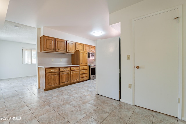 10335 W Mission Ln, Sun City, AZ 85351 - kitchen with light countertops, baseboards, brown cabinets, and stainless steel appliances