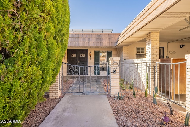 10335 W Mission Ln, Sun City, AZ 85351 - doorway to property with mansard roof, fence, brick siding, and a gate
