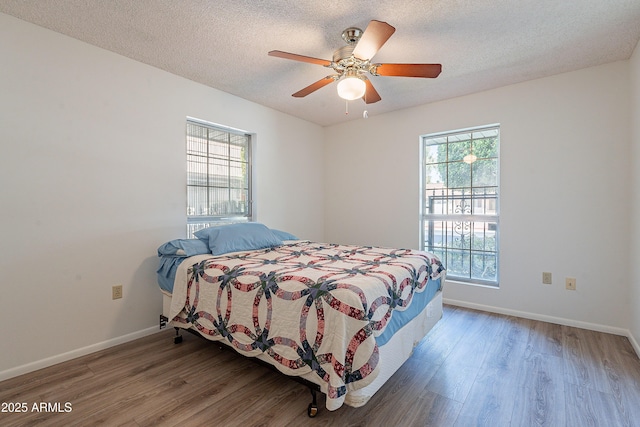 10335 W Mission Ln, Sun City, AZ 85351 - bedroom featuring multiple windows, a textured ceiling, baseboards, and wood finished floors