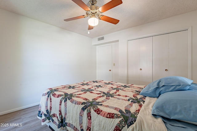 10335 W Mission Ln, Sun City, AZ 85351 - bedroom with visible vents, baseboards, a textured ceiling, and wood finished floors