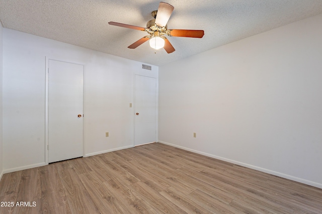 10335 W Mission Ln, Sun City, AZ 85351 - unfurnished bedroom with light wood finished floors, visible vents, a textured ceiling, and baseboards