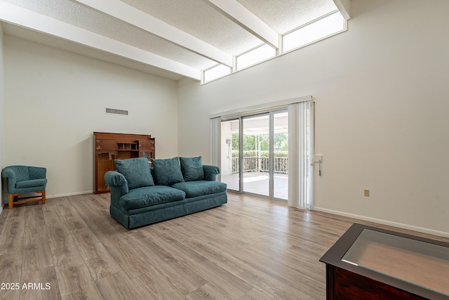 10335 W Mission Ln, Sun City, AZ 85351 - living room featuring baseboards, beam ceiling, a high ceiling, a textured ceiling, and light wood-type flooring
