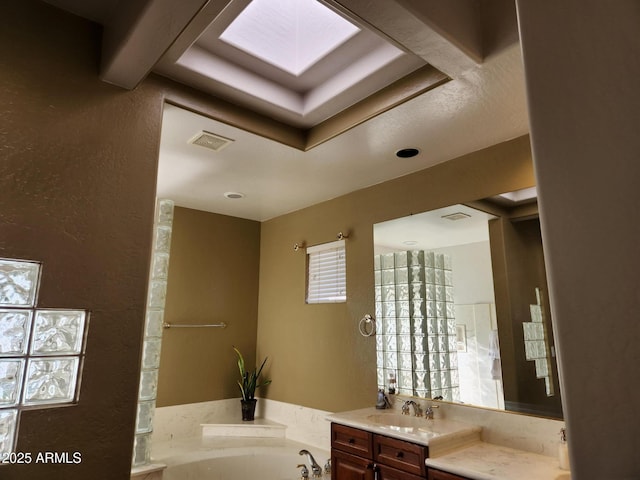 bathroom with vanity, a skylight, and a bathing tub