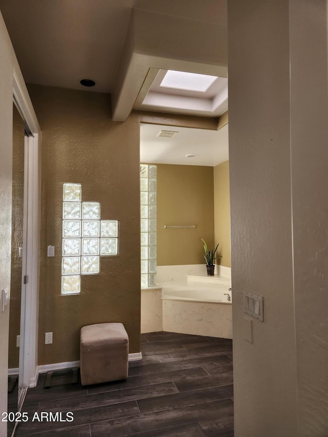 bathroom featuring a tub to relax in, a skylight, and wood-type flooring