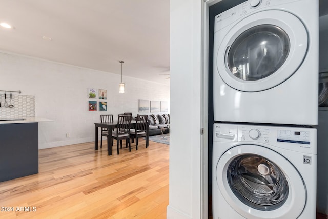 laundry area with stacked washer and dryer and hardwood / wood-style floors